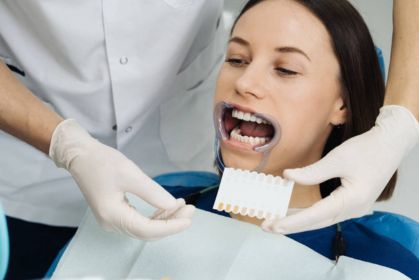 Dentista verificando e selecionando a cor dos dentes jovens mulheres - Foto, Imagem