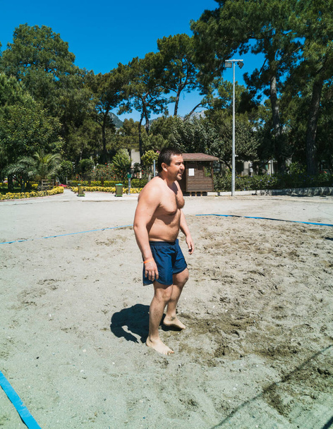Férfi 35-45 éves játszik strandröplabda a homokban a tenger mellett - Fotó, kép