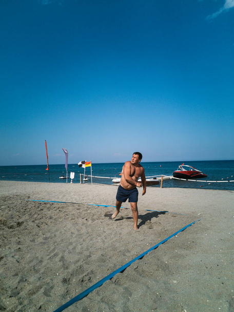 Hombre 35-45 años juega voleibol de playa en la arena junto al mar - Foto, imagen