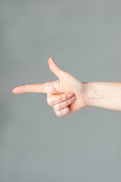 Woman hand showing forefinger in gun sign on a white isolated background. - Foto, Imagem