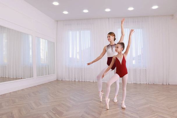 Kleine Ballerina und ihr Lehrer üben im Studio Tanzbewegungen ein. Raum für Text  - Foto, Bild