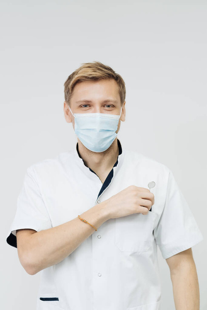 Ο επαγγελματίας οδοντίατρος φοράει προστατευτική μάσκα προσώπου. - Φωτογραφία, εικόνα