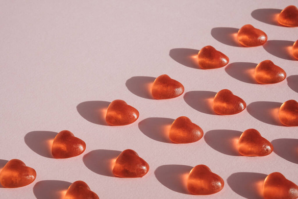 Heart shaped candy pattern diagonally arranged on pastel pink background. Romantic minimal flat lay - Foto, Imagen