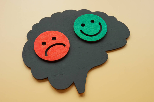Bipolar disorder concept. Brain shape with happy and sad emoticons. - Foto, afbeelding