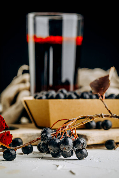 Fresh aronia berries and berry juice in a glass - Fotó, kép
