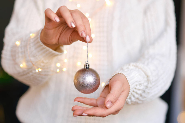 Woman in white warm woolen sweater holding toy decorative ball in hands, copy space. Christmas, new year holiday celebration concept. Selective focus, Cozy Vibes - Fotografie, Obrázek