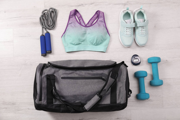 Grey bag and sports accessories on floor, flat lay - Foto, afbeelding