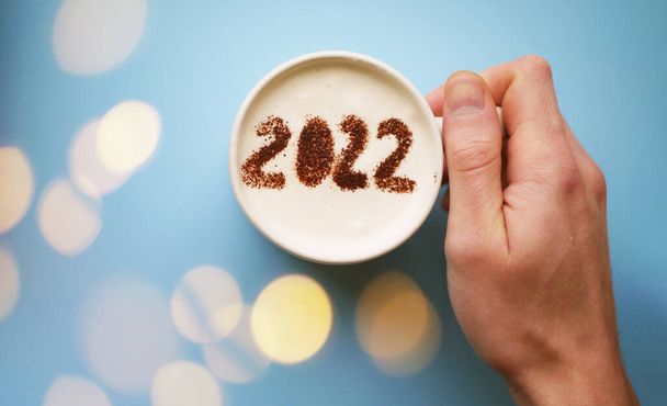 Taza de café de mano con 2022 números. Saludo de Año Nuevo. Nuevo concepto de inicio - Foto, imagen