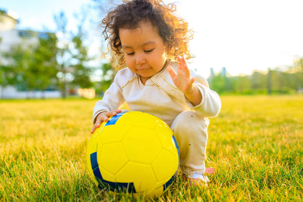 afro american cheerful curly girl playing a yellow ball in sunset park - 写真・画像