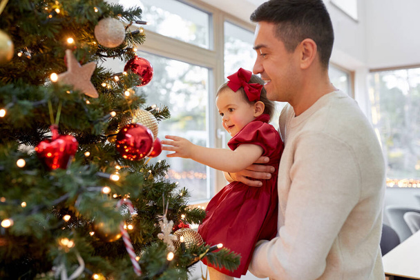 glücklicher Vater und kleines Mädchen schmücken Weihnachtsbaum - Foto, Bild