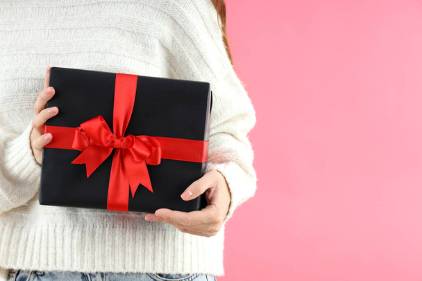 Woman holds gift box on pink background - Foto, afbeelding
