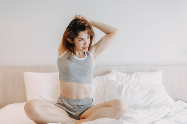 Attractive woman in underwear stretching on the bed in the morning. - 写真・画像