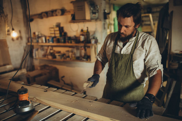 Un carpintero masculino trabaja en el taller. - Foto, Imagen