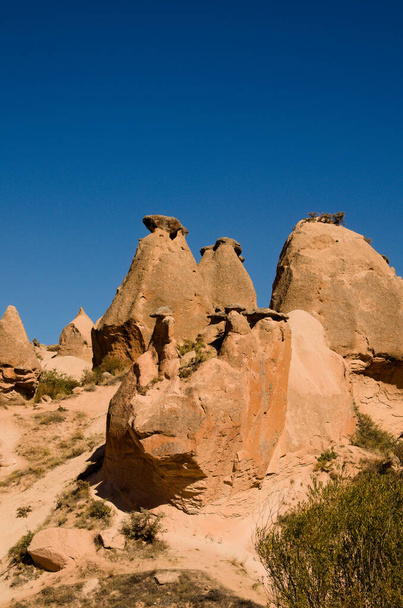 Vue panoramique pittoresque des formations géologiques typiques de la Cappadoce. Montagne dans la lumière du coucher du soleil en arrière-plan. Incroyable rochers de grès en forme contre le ciel bleu. Belle journée ensoleillée d'automne. - Photo, image