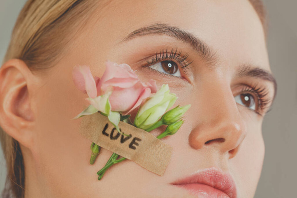 Liebeskonzept. Close-up Frau Gesicht mit Rosen Blumen und Liebe Inschrift - Foto, Bild