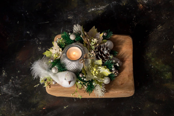 Украшение новогоднего или рождественского стола. Ветки елки, искусственные цветы и свечи на деревянном подносе на столе крупным планом - Фото, изображение