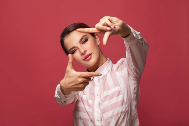 Young woman over red wall smiling and making photo gesture - Foto, Imagem