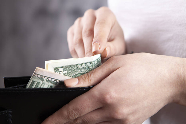 a young girl pulls out bills from a wallet - Fotó, kép