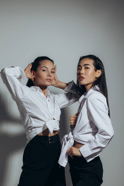 Two young women with wet hair and water drops on face pose in studio. - Foto, Imagem