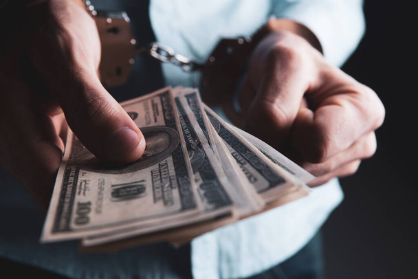 man in handcuffs holding money - Foto, afbeelding