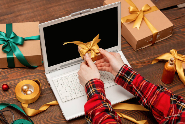 kobieta pracująca z laptopem i pakująca pudełka z prezentami na stole. - Zdjęcie, obraz