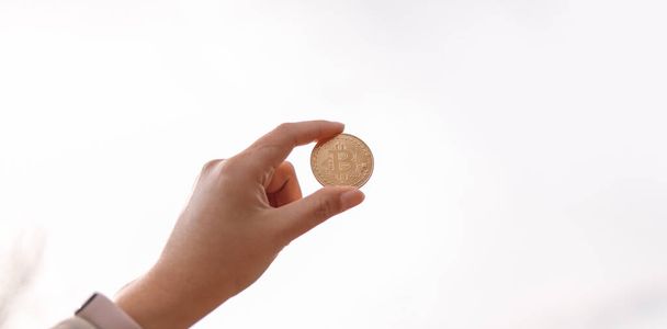 Αγνώριστο γυναικείο χέρι δείχνει bitcoin μετρητά κέρμα με αντίγραφο χώρου στον ουρανό φόντο - Φωτογραφία, εικόνα