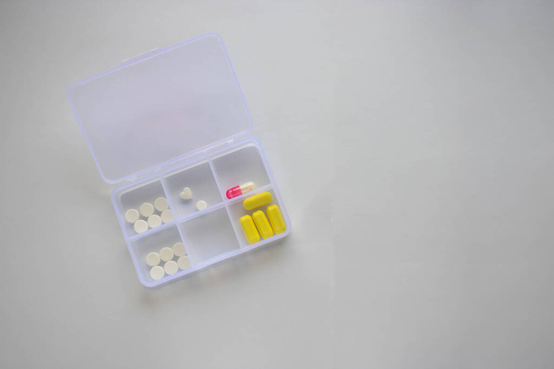 Ci sono capsule e compresse su uno sfondo bianco nella scatola dell'organizzatore della pillola. Il concetto di medicina.Nefrologia, glomerulonefrite. - Foto, immagini