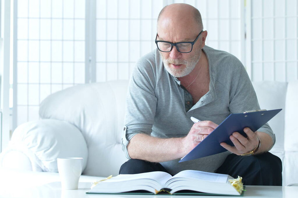 senior man with book working at home  - Foto, Bild