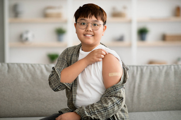 Χαριτωμένο παχουλό κορεάτικο παιδί εμβολιάστηκε, δείχνοντας κολλητική ταινία - Φωτογραφία, εικόνα