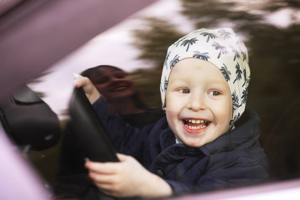 Mały chłopiec bawiący się kierownicą w samochodzie. Ręce małego dziecka jadącego samochodem. instrukcja jazdy w dzieciństwie - Zdjęcie, obraz