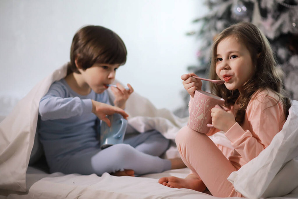 Семья с детьми, веселящимися на кровати под одеялом во время рождественских каникул. - Фото, изображение