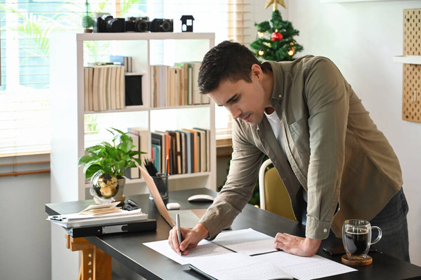 Молодой человек, работающий с финансовыми документами на дому. - Фото, изображение