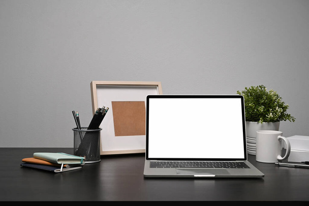 Computer-Laptop, Topfpflanze, Kaffeetasse und Bilderrahmen auf schwarzem Tisch. - Foto, Bild