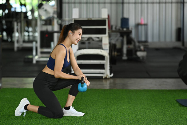Young fitness woman working out with kettlebells in gym.  - Fotó, kép