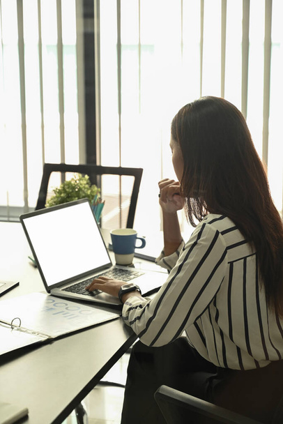 Vista laterale della donna d'affari che analizza le informazioni finanziarie sul computer portatile. - Foto, immagini