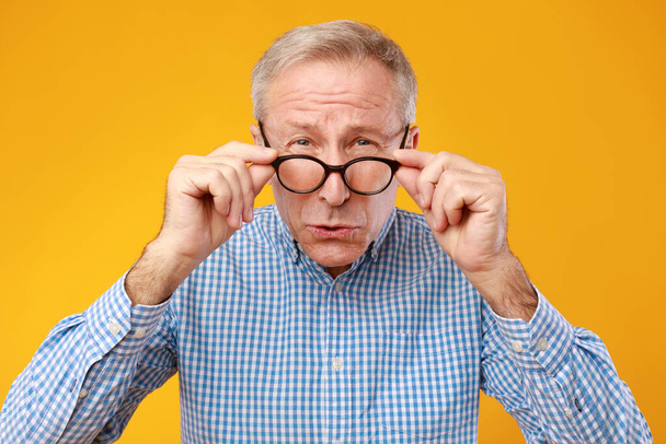 volwassen man squinting het dragen van bril, kijken naar camera - Foto, afbeelding