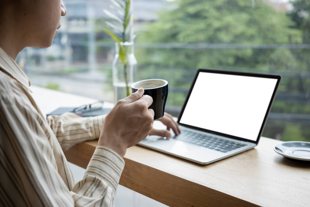 Oříznutý záběr podnikatel drží šálek kávy a pracuje s notebookem. - Fotografie, Obrázek