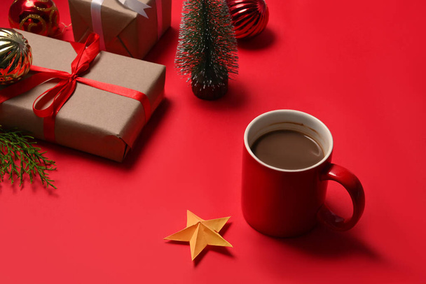 Cup of hot coffee and Christmas gift boxes on red background. - Фото, зображення