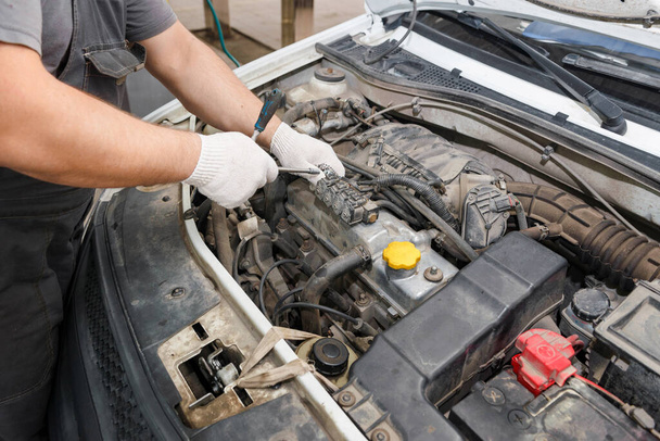 Mechanic repairing engine on a vehicle. Professional mechanic is checking for engine malfunction - Фото, изображение