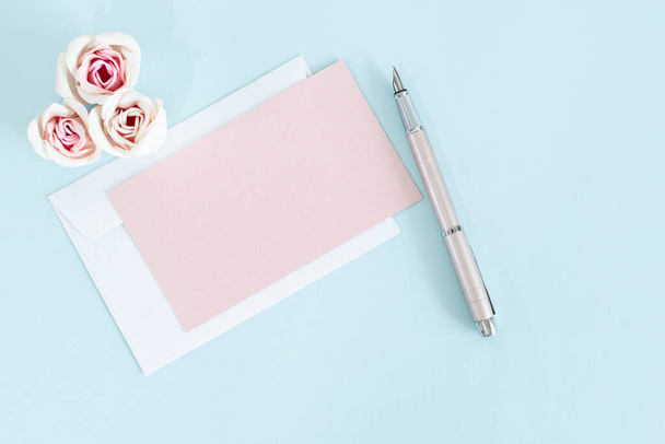 A top view of envelopes with roses and a pen on a blue surface - Photo, Image