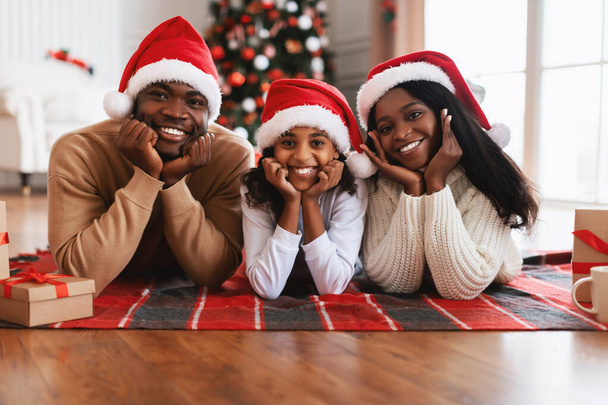 Feliz familia negra en los sombreros de Santa Claus celebrando Navidad - Foto, Imagen
