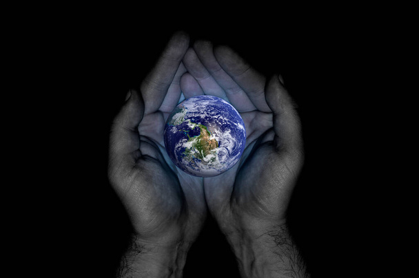 Τα χέρια του ανθρώπου κρατούν τον πλανήτη Γη σε μαύρο φόντο από κοντά. Παγκόσμια Ημέρα Περιβάλλοντος - Φωτογραφία, εικόνα