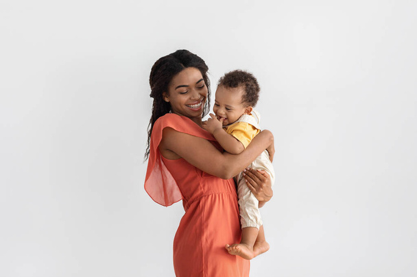 Mutter und Baby. Porträt einer fröhlichen schwarzen jungen Mutter, die ein Kleinkind hält - Foto, Bild