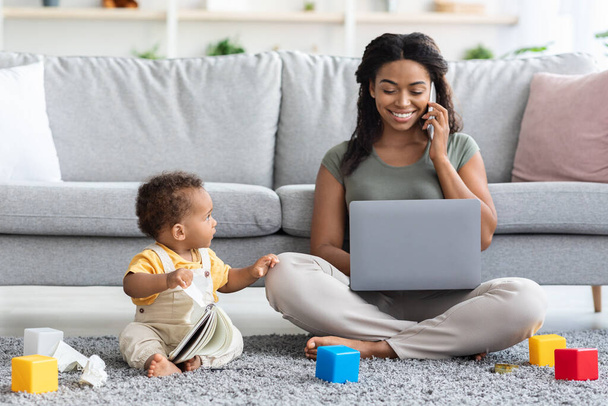 Black Woman Working On Laptop And Taking Care Of Her Infant Child - Foto, afbeelding