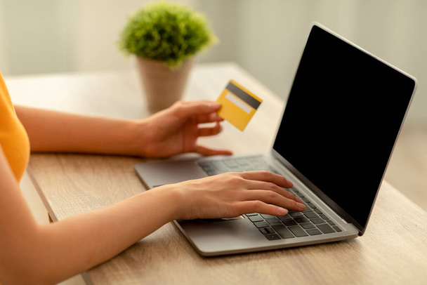 Señora irreconocible con el ordenador portátil y la tarjeta de crédito de compras sin contacto en línea, maqueta para el diseño del sitio web en la pantalla en blanco - Foto, Imagen
