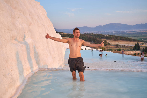 Happy man traveler swimming at Pamukkale Natural Park among white travertine in Turkey .Young man rest in Pamukkale natural park in pool with beautiful view.                       - Foto, immagini