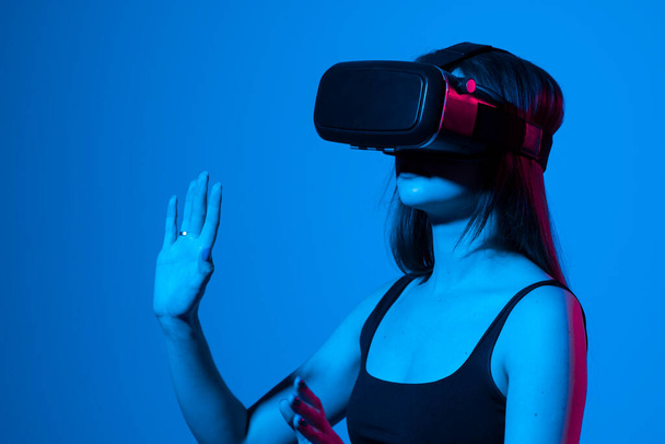Young woman using VR headset helmet to play simulation game. Watching virtual reality 3d video. Girl in VR goggles looking around. - Foto, imagen