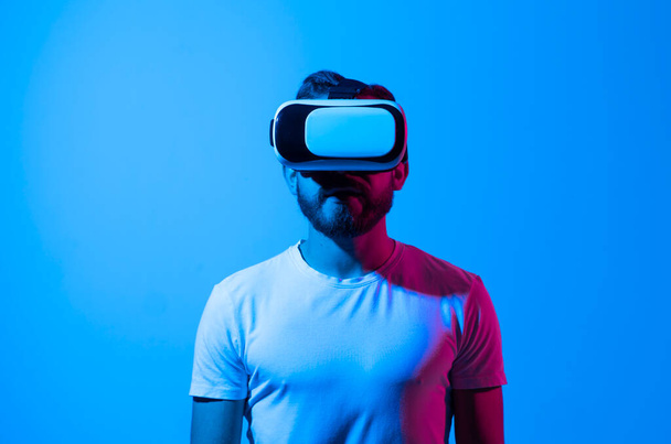 Bearded man using VR headset helmet to interacts with metaverse using swipe and stretching gestures. Watching virtual reality 3d video. Man in VR goggles looking around. - Foto, imagen