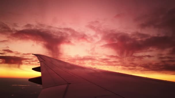 Vue de la fenêtre de l'avion sur l'aile à l'heure du coucher du soleil pittoresque avec ciel rose dramatique - Séquence, vidéo