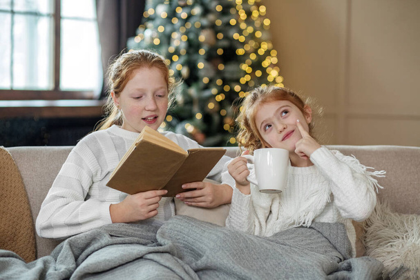 A gyerekek mosolyognak. Karácsonykor. Meleg fehér kötött pulóver. Hangulatos otthon. - Fotó, kép